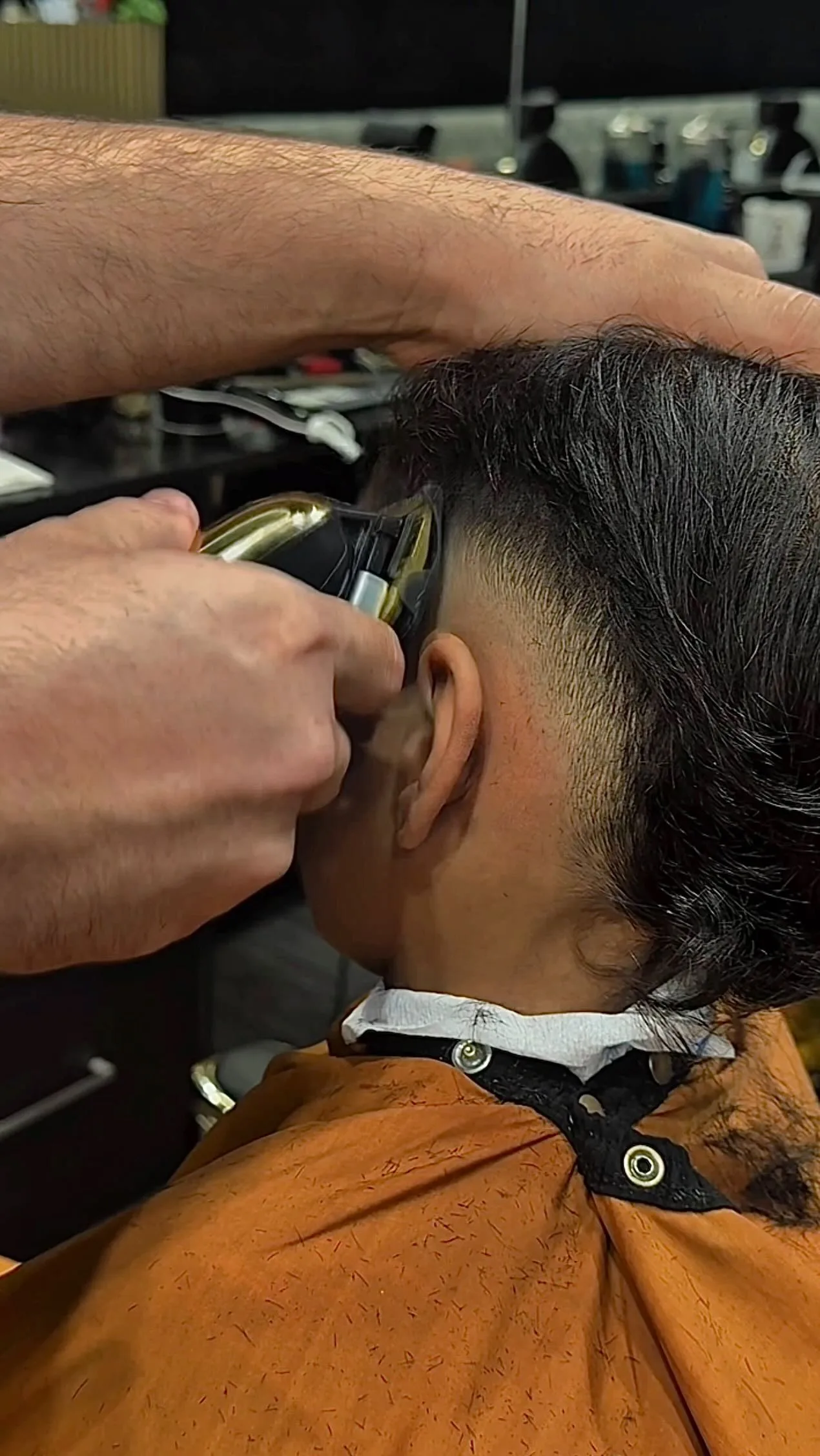 Barber's hands and gold clippers detailing the nape