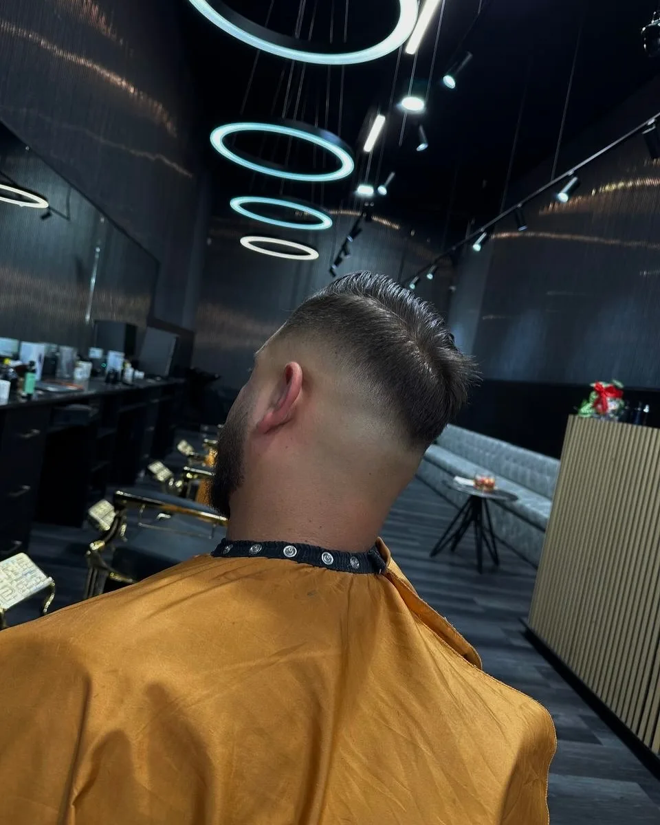 Oxygen Barbershop full interior — mirrored aisle of brass chairs beneath neon halo rings