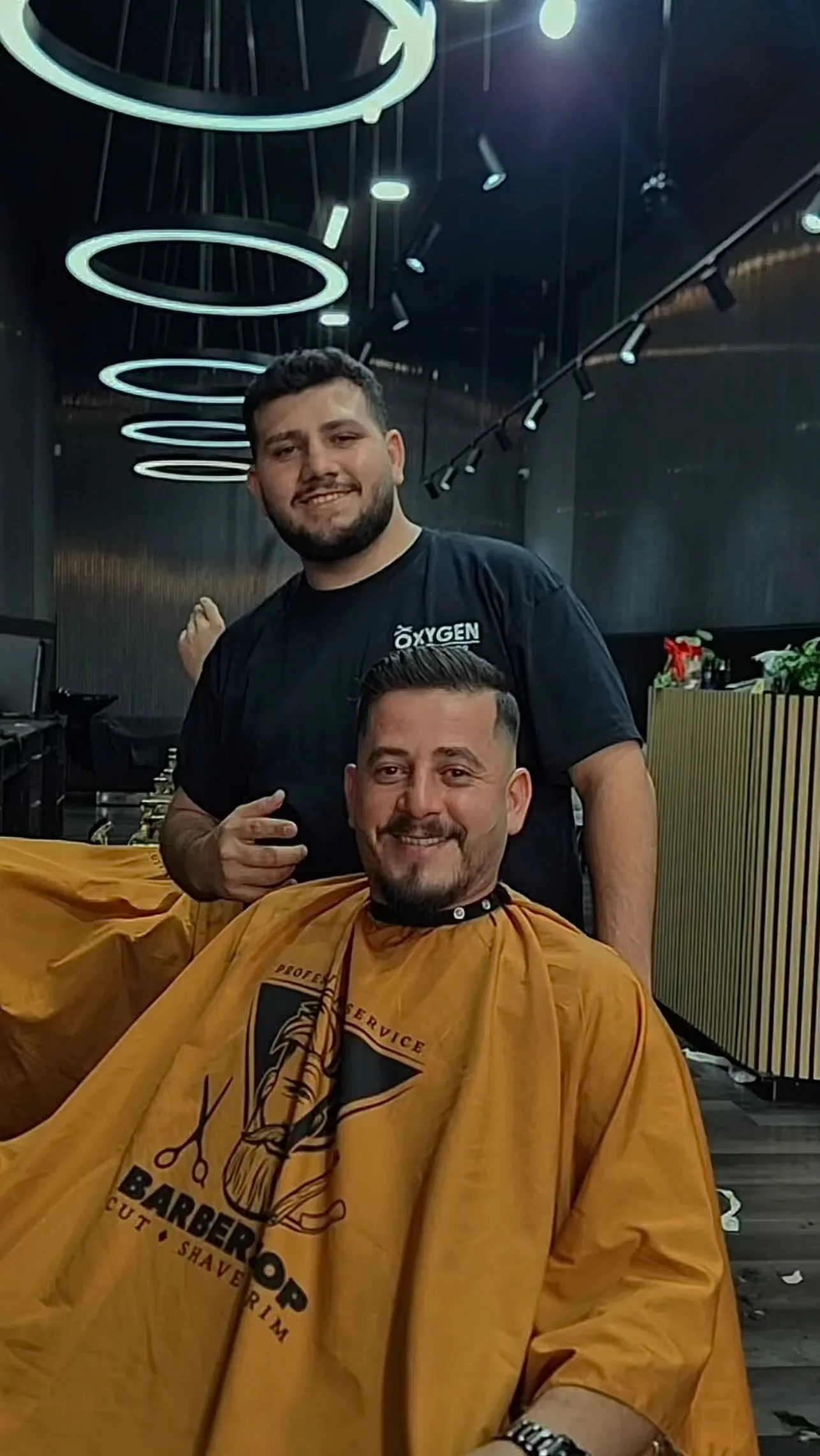 Barber standing behind a seated client — Oxygen Barbershop